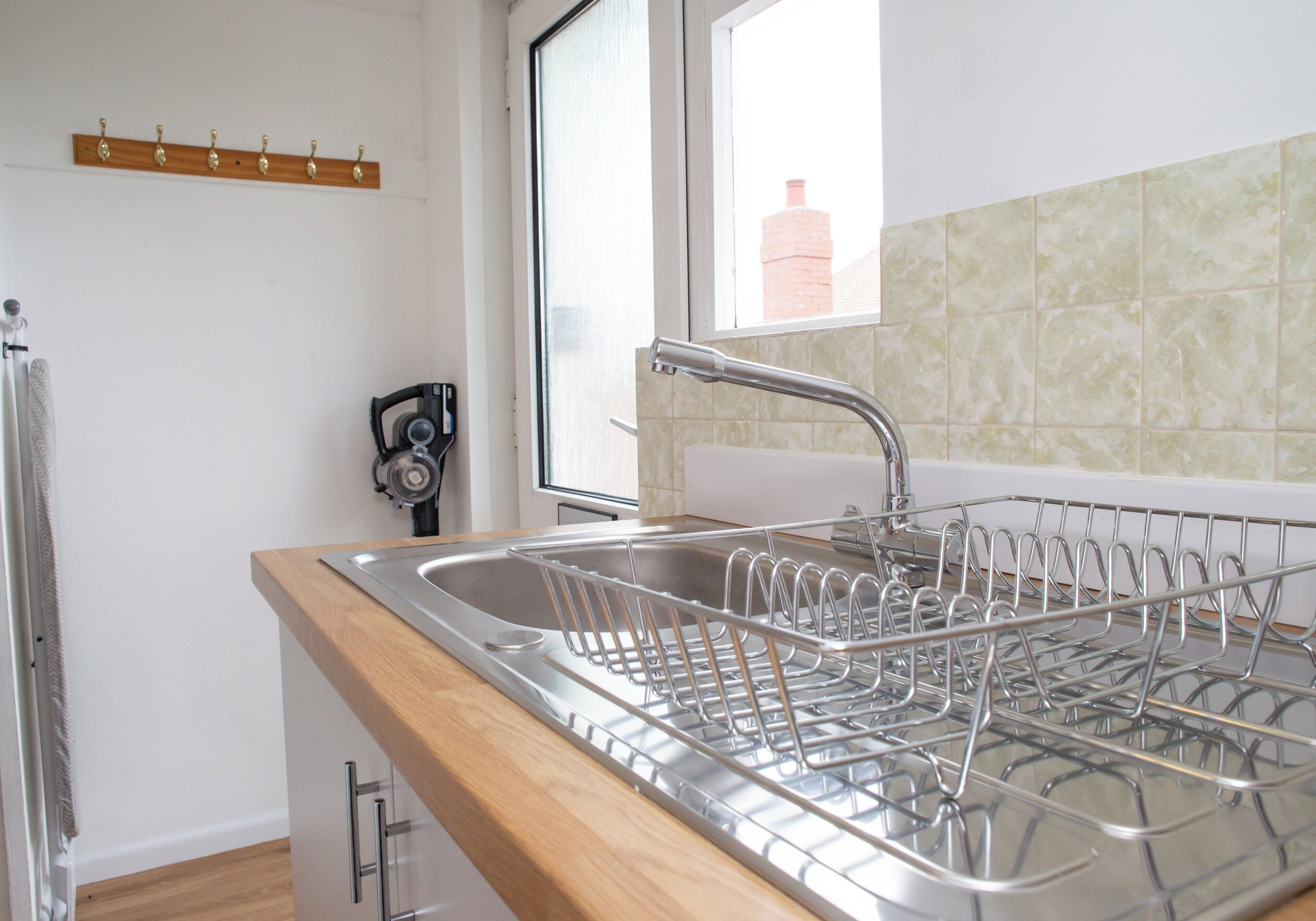 A kitchen with a stainless steel sink, wooden countertop, and a window with a view of a brick building.