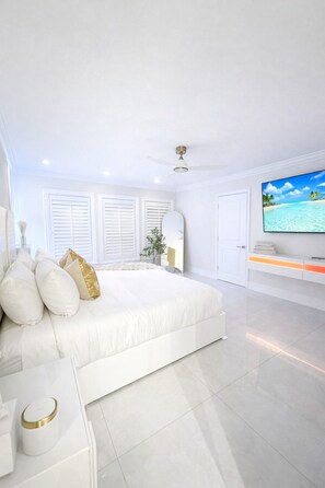 Ein modernes Schlafzimmer mit einem großen Bett, einem Fernseher und einem Deckenventilator.