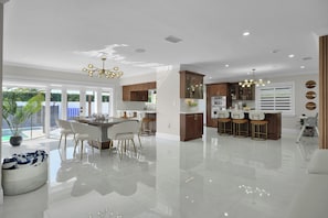 Eine moderne Küche mit Essbereich, großen Fenstern und einer zentralen Kochinsel.