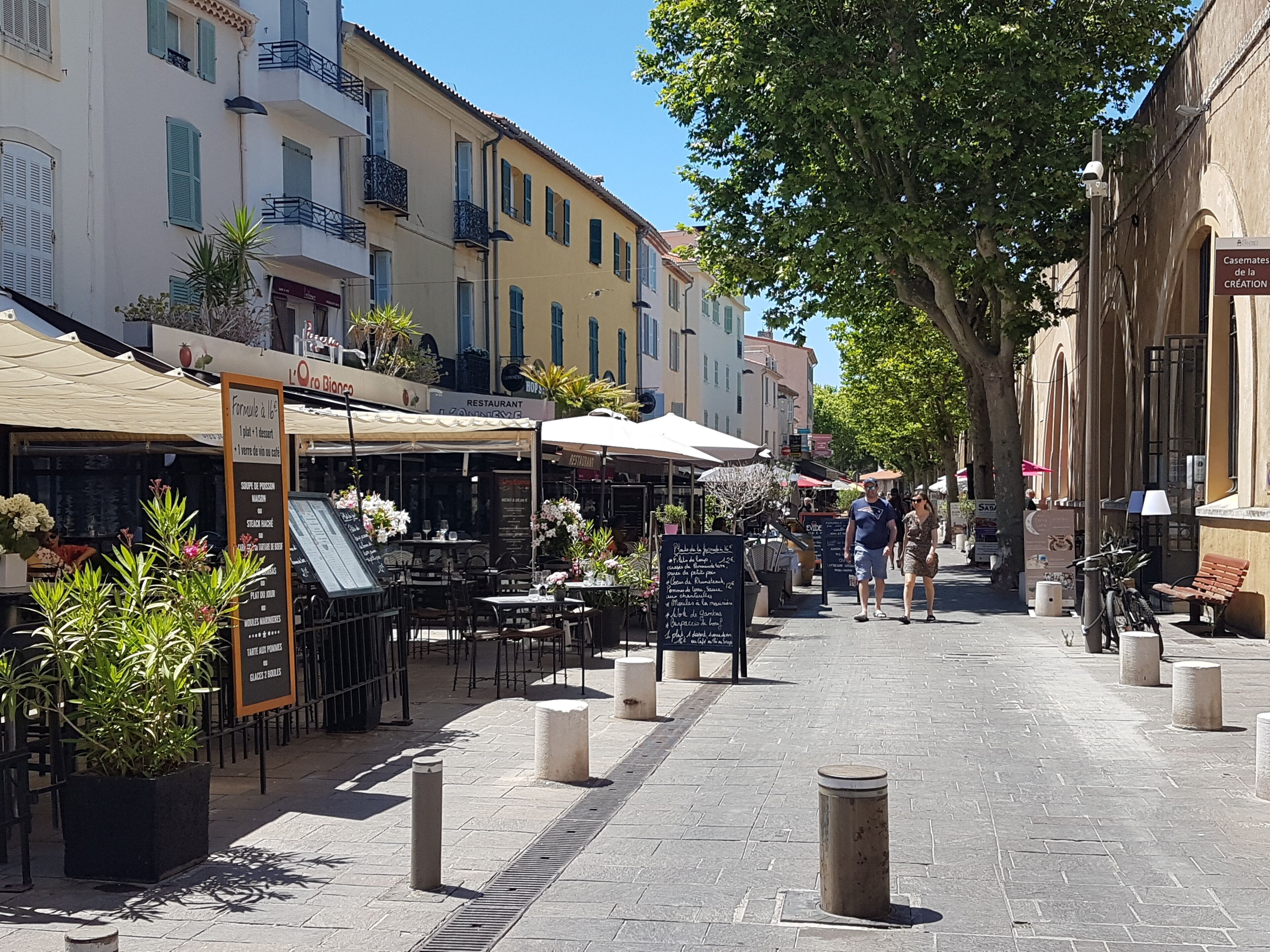 Eine Straße mit Außenplätzen, einer Speisekarte und einem Schild mit der Aufschrift 'L'Oran D'Ange'.
