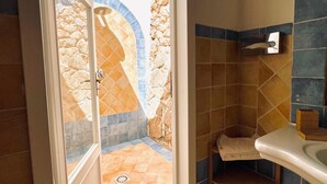 Une salle de bain avec un mur en pierre, un espace douche et un lavabo.