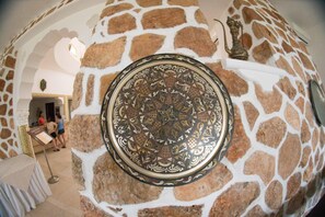 Un muro de piedra con una placa de metal decorativa, un arco de piedra y un cartel.