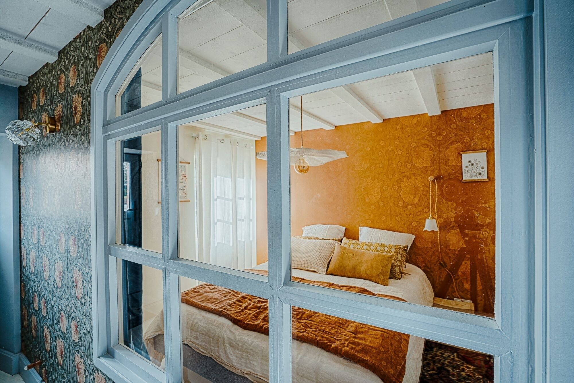 Une pièce avec un lit, une fenêtre et un mur décoré de motifs.