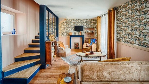 Sala de estar com escada, lareira e papel de parede estampado.