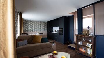 Een moderne woonkamer met een bank, salontafel en een eethoek met behang met een patroon.