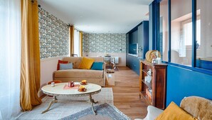 Uma sala de estar com sofá, mesa de centro redonda e um espaço de jantar com mesa e cadeiras.