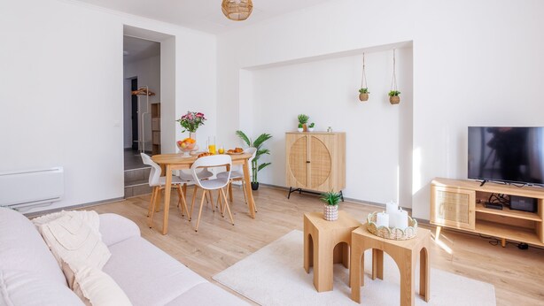 Een moderne woonkamer met een bank, eettafel, stoelen, een televisie en een kast.