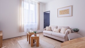 Een woonkamer met een bank, een salontafel, een bijzettafeltje, een deur en een lijst met een foto aan de muur.