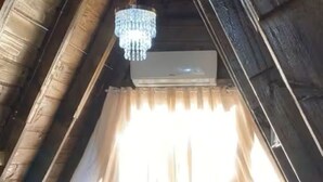 Ein Schlafzimmer mit einem Bett, Kissen, einer Deckenleuchte und einem Fenster mit Vorhängen.