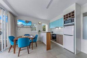 A modern kitchen with white and blue cabinets, a built-in oven, and a refrigerator. - Ocean Rise at Airlie Two (Airlie Beach)