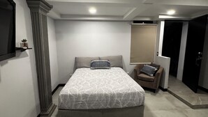 A bedroom with a bed, a nightstand, a chair, a mirror, and a door. - Studio 05 in Santa Ana Central, Convenient, and Comfortable (Santa Ana)