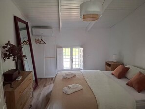 A bedroom with a bed, bedside tables, a dresser, a mirror, and a window with daylight.