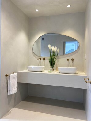 A bathroom with two white sinks, a large oval mirror, and a towel rack. - Casa Romeriko: Private Pool and Views of Ricote (Rambla)