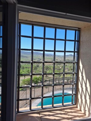 A window with a view of a pool and a landscape.