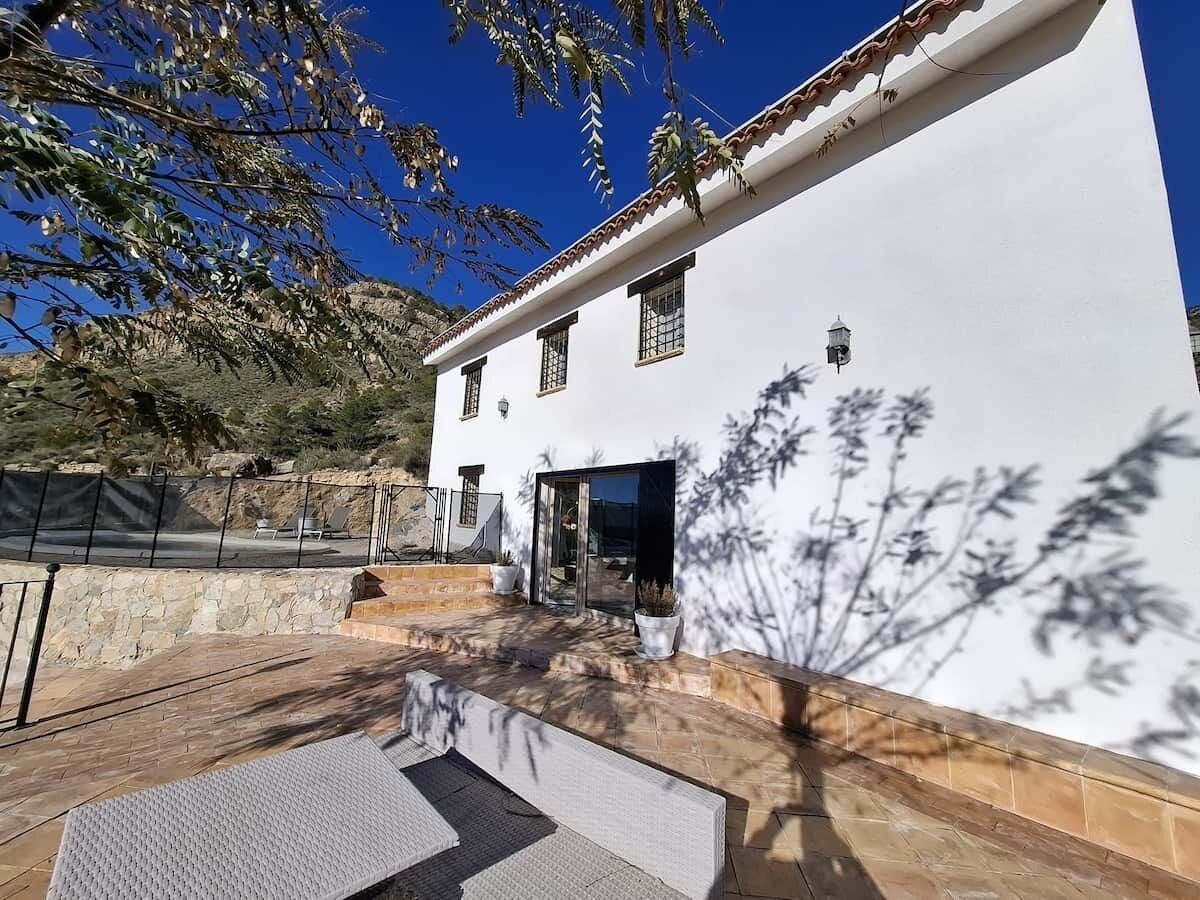 A white building with a tiled patio, a door, and a small window.