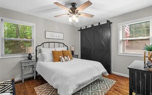 A bedroom with a bed, a ceiling fan, a nightstand, a dresser, and a window with blinds. - North GA Mountain retreat with fire pit near Helen/ Dahlonega wineries & hiking (Cleveland)