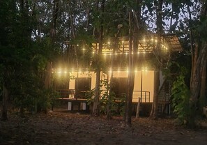 Eine rustikale Holzhütte mit Lichterketten, umgeben von Bäumen.