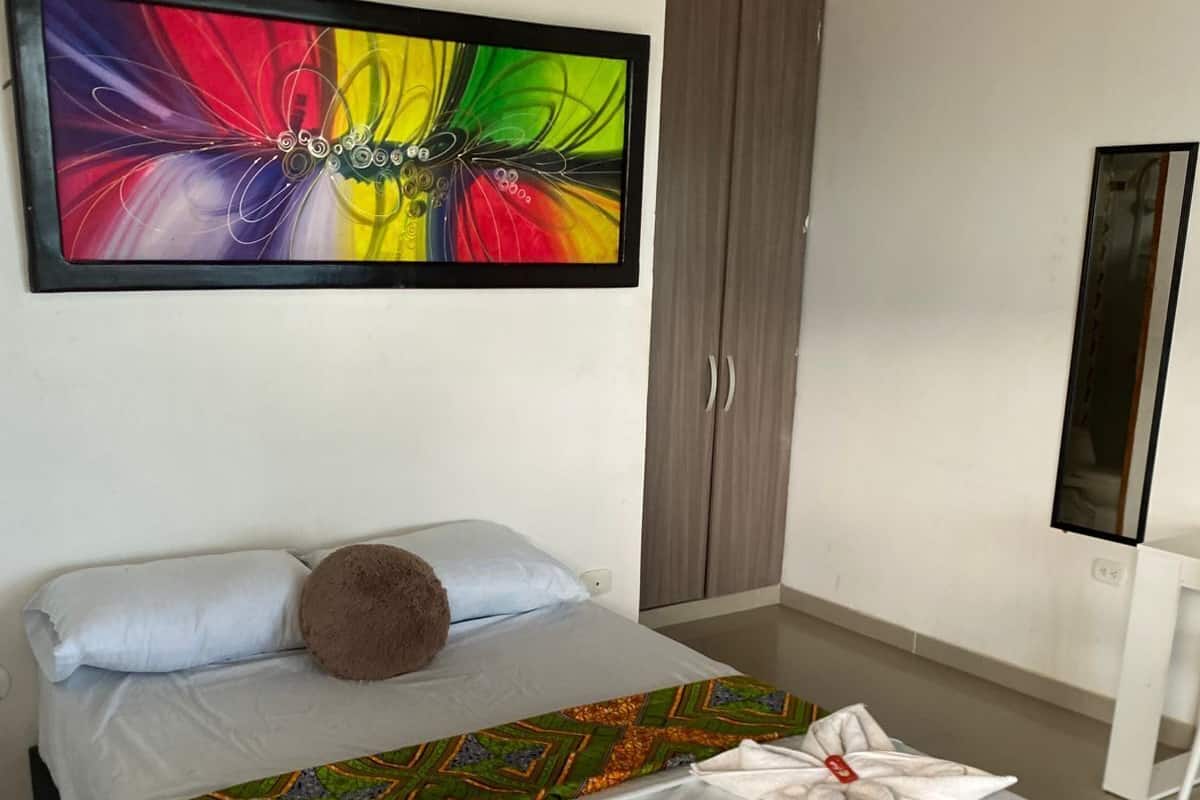 Une chambre d’hôtel avec un lit, un grand tableau abstrait, une armoire et un téléviseur.