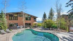 A swimming pool with lounge chairs, a patio area, and a building with large windows. - Sonnenblick by Snowmass Vacations (Snowmass Village)