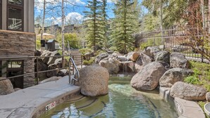 A hot spring area with large rocks, a wooden deck, and a stone building with a stone facade. - Sonnenblick by Snowmass Vacations (Snowmass Village)