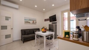 A compact kitchen with a dining table, a sofa, a TV, and a refrigerator. - ZenOrlando House Apartament Sea view+Parking 2S (Taormina)
