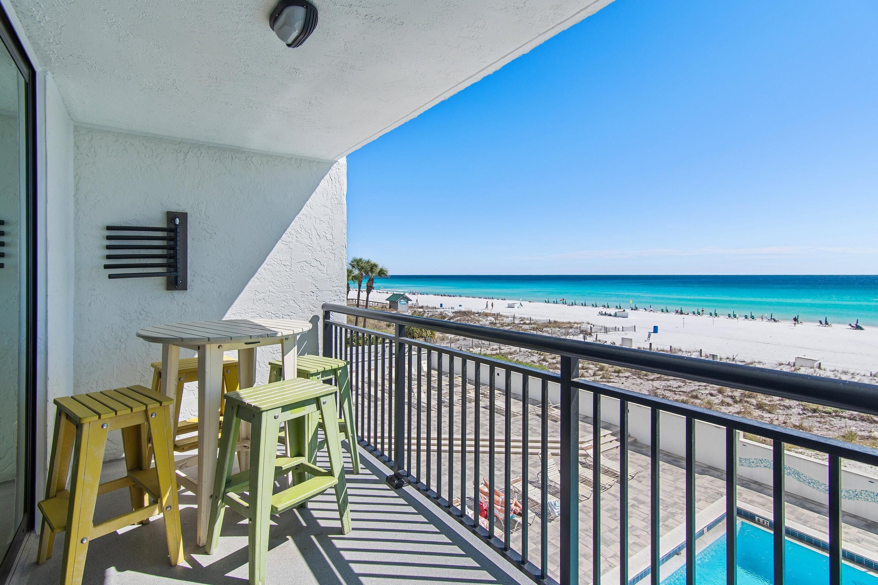A balcony with a view of a beach and a pool.