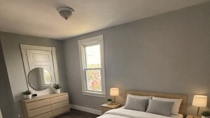 Ein Schlafzimmer mit Bett, Kommode, Nachttischen und einem Fenster.