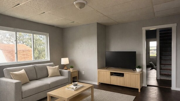 Ein modernes Wohnzimmer mit Sofa, Couchtisch, Fernseher und einer Treppe zu einer weiteren Ebene.