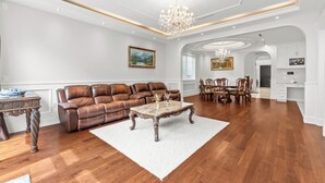 Uma sala de estar ampla com um sofá de couro marrom, uma mesa de centro de madeira e um candelabro.