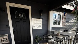 Une terrasse en bois avec une porte noire, une petite table et deux chaises.