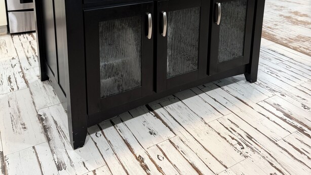 Une cuisine avec des meubles de couleur noire, un plan de travail en bois et des appareils électroménagers en acier inoxydable.