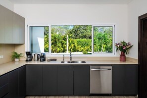 Een moderne keuken met een groot raam, een vaatwasser en een koffiezetapparaat.