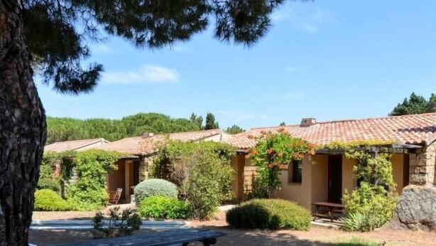 A rustic building with a tiled roof, surrounded by greenery and a picnic table.