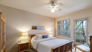 Une chambre à coucher avec un lit, des tables de chevet, un ventilateur de plafond et des fenêtres.
