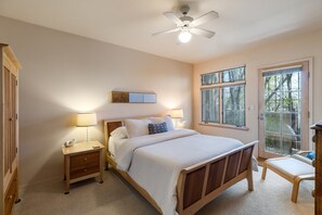 Ein Schlafzimmer mit Bett, Nachttischen, Deckenventilator und Fenstern.