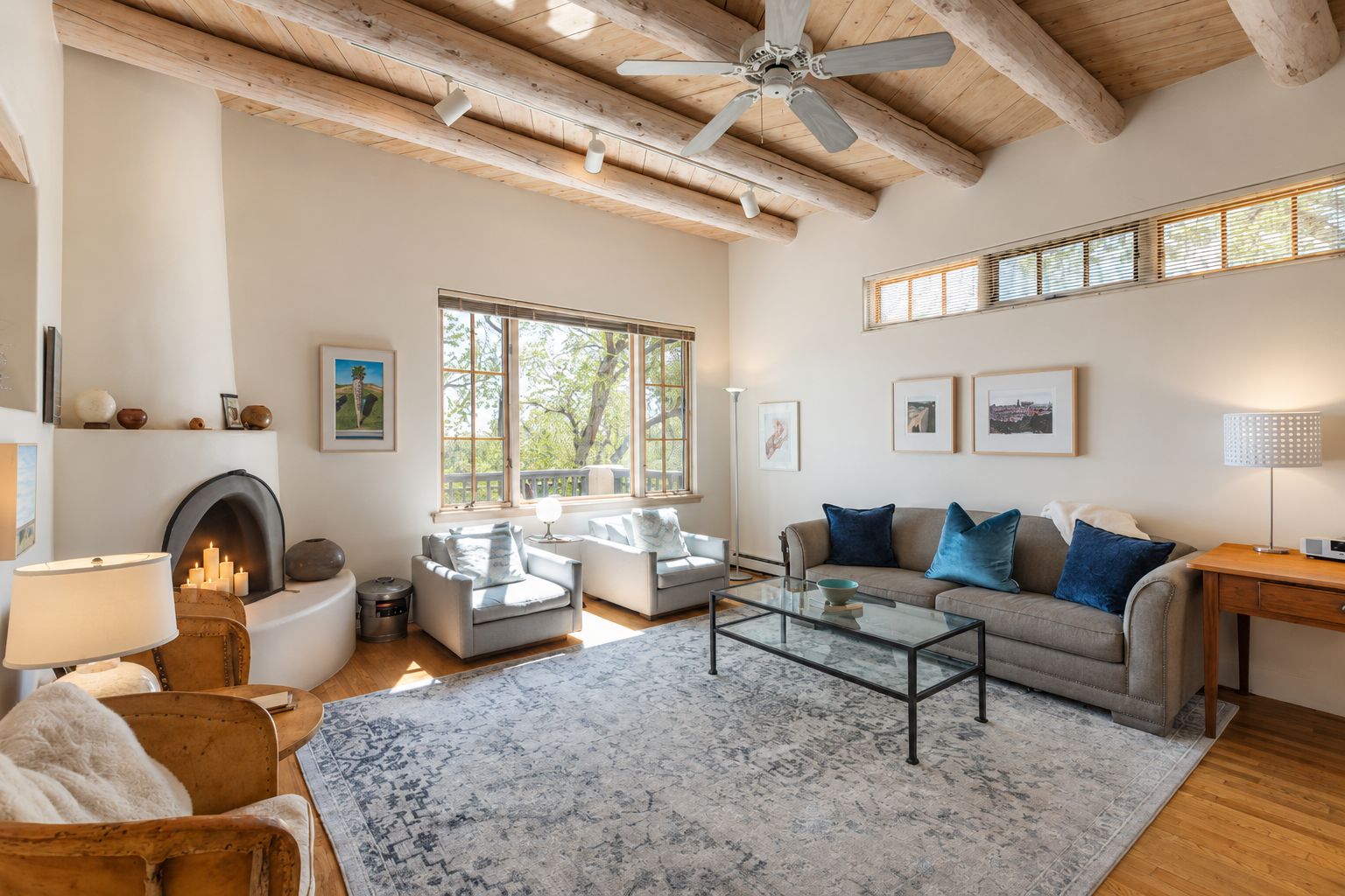 A spacious living room with a fireplace, two sofas, a coffee table, and a ceiling fan.