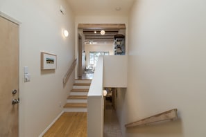Eine Treppe mit Holzbodenstufen führt zu einer Zwischenebene, links eine weiße Tür und ein gerahmtes Bild an der Wand.