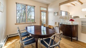 Une salle à manger avec une table ronde, des chaises, un buffet et un ventilateur de plafond.
