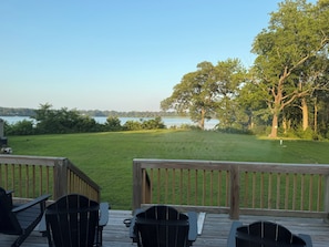 Eine Terrasse mit Stühlen mit Blick auf eine Wiese und einen See.