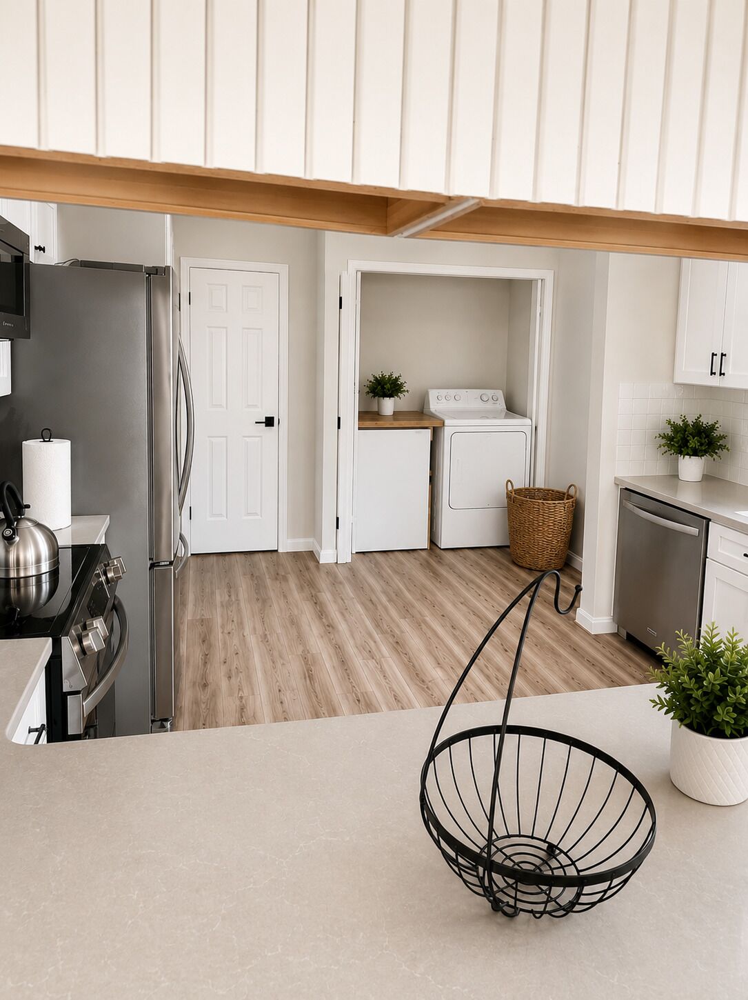 A modern kitchen with a stainless steel refrigerator, a stove, a washing machine, and a dishwasher.