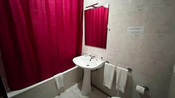 A bathroom with a white sink, a toilet, and a red shower curtain.