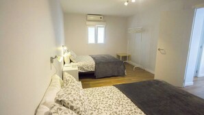 A bedroom with two beds, a window, an air conditioner, and a door. - Home2Book Family Stay Near Seville Center (Seville)