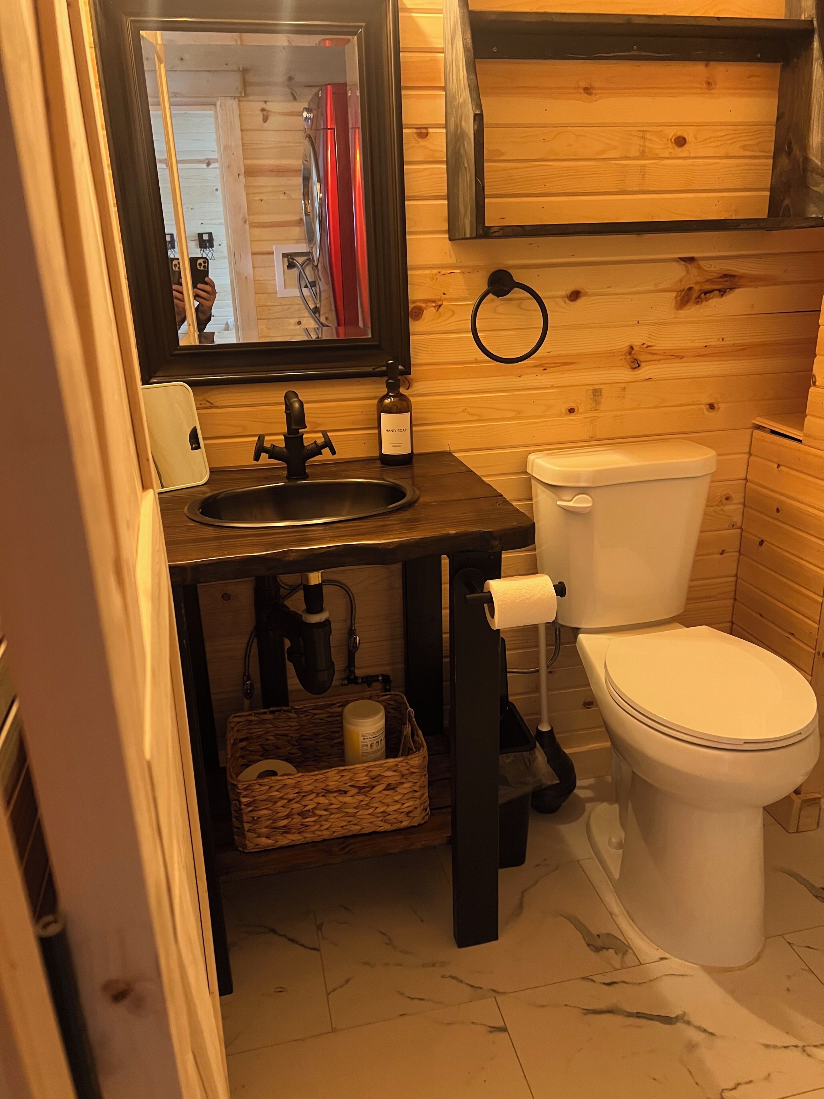 Un baño pequeño con un mueble de tocador de madera, un lavabo, un inodoro y un espejo.