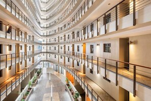 Un atrium à plusieurs niveaux, doté d’un espace central ouvert, de rampes et de jardinières.