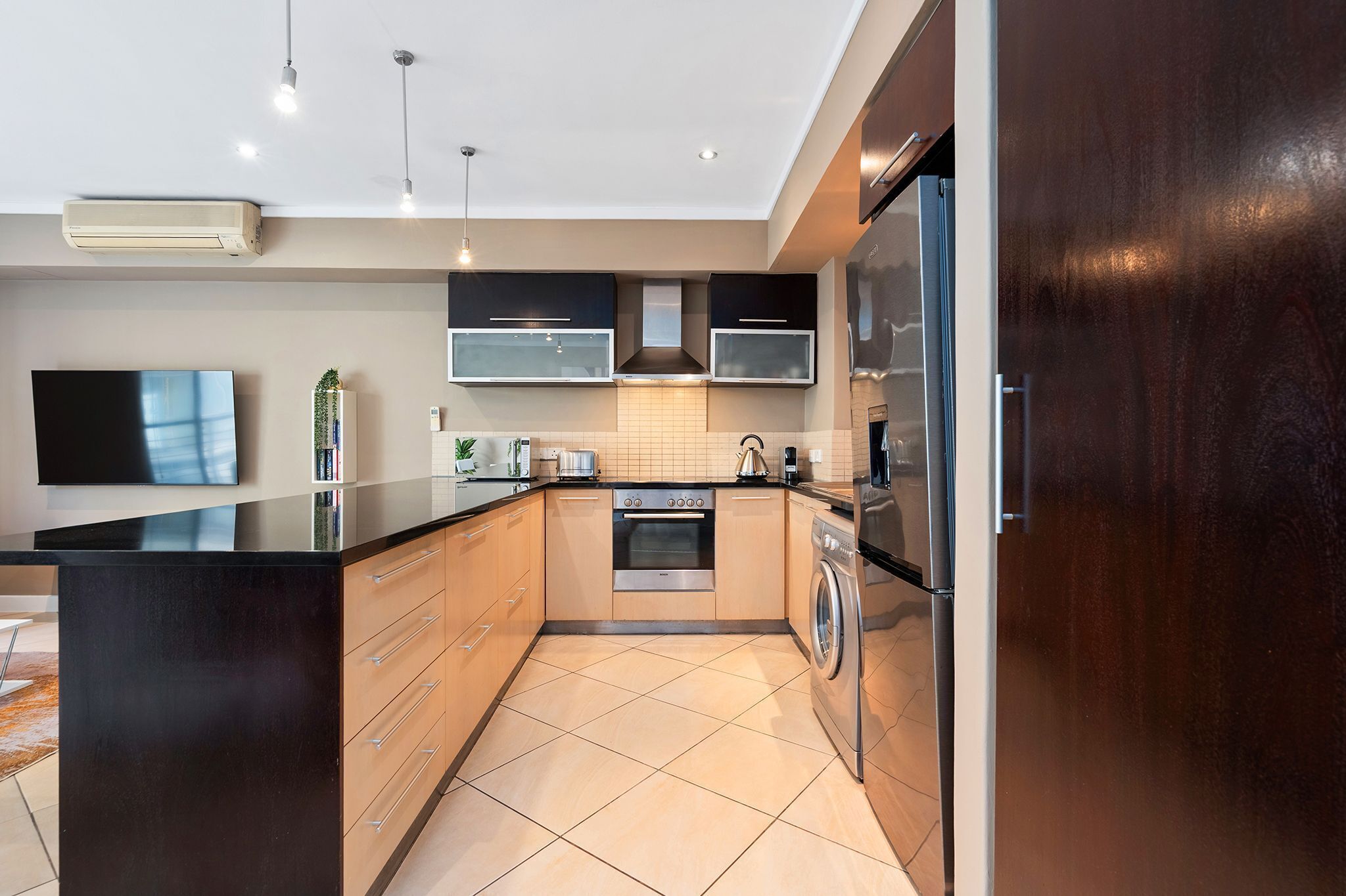 A modern kitchen with a central island, built-in oven, microwave, and stainless steel appliances.