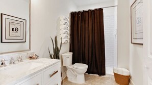 Een badkamer met een wit toilet, een wastafel met een marmeren blad en een lijst met een foto aan de muur.