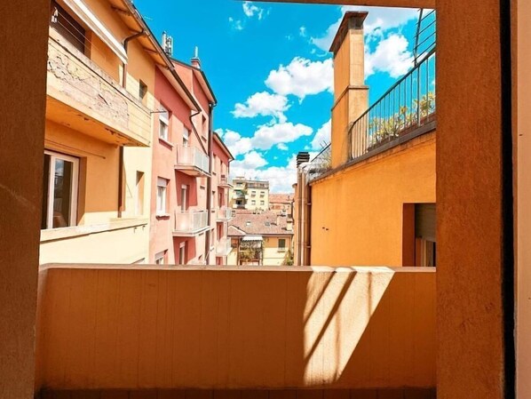 A narrow alleyway between buildings with balconies, clear sky, and a distant view of a building with a dome. - Ostello Bello Bologna (Bologna)