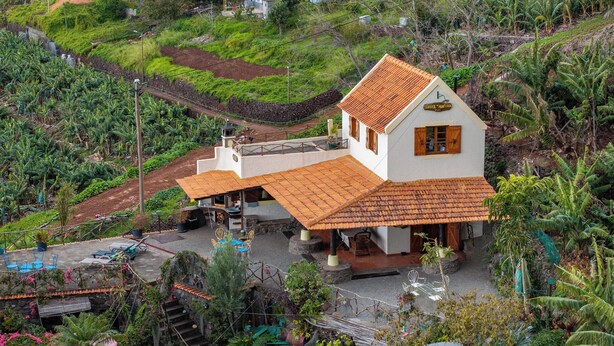 Ein Haus mit Ziegeldach, umgeben von üppiger Vegetation und einem kleinen Poolbereich.