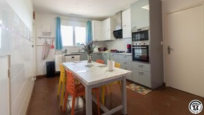Una cucina compatta con tavolo, sedie e frigorifero.