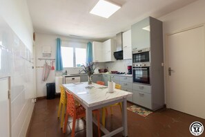 A compact kitchen with a dining table, chairs, and a refrigerator. - House Venitia 14 persons (AUSSONNE)